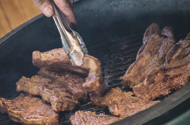 Korean shortrib wordt omgedraaid op de kamado barbecue van Big Green Egg met een vleestang