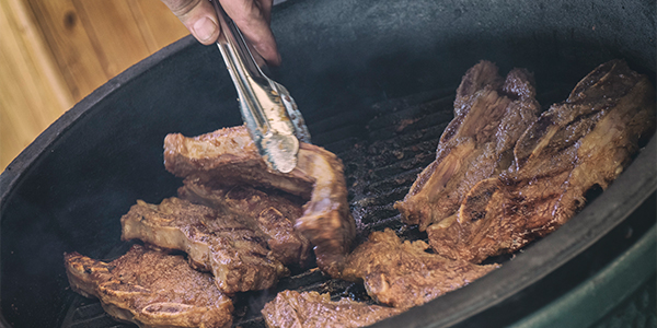 Korean shortrib wordt omgedraaid op de kamado barbecue van Big Green Egg met een vleestang