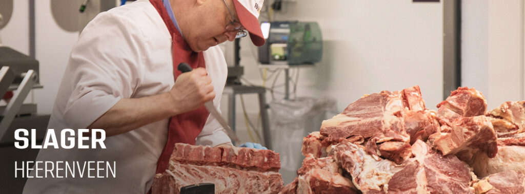 Slager snijdt vlees achter de werkbank in de slagerij van HANOS Heerenveen